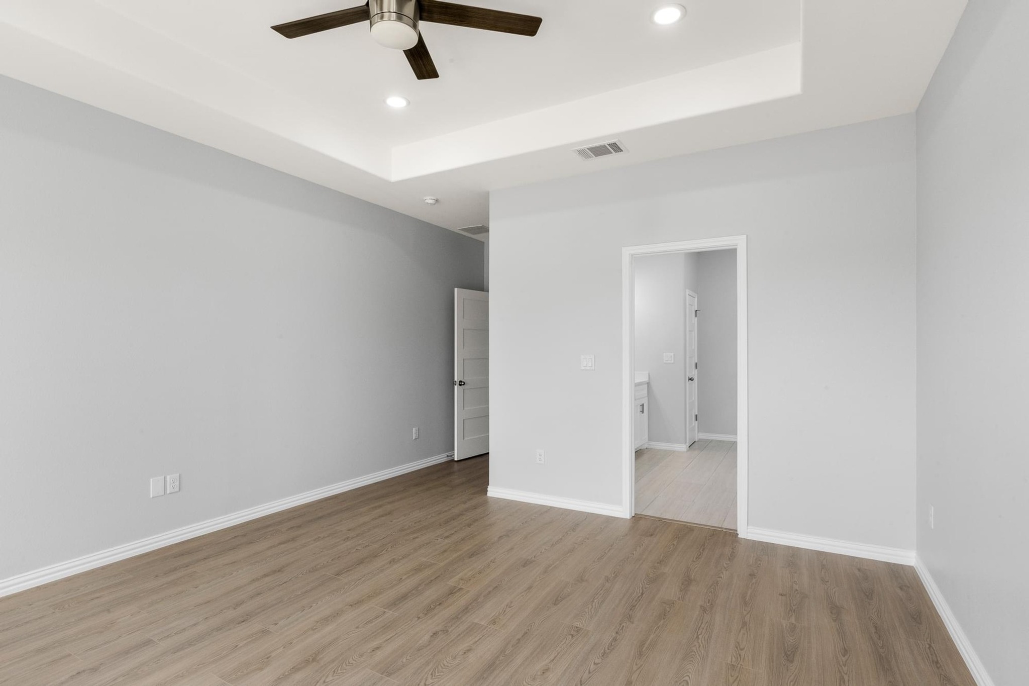 1136 County Road 484 Elgin, TX 78621 - Photo 18 of 37 Unfurnished bedroom featuring a raised ceiling, light wood-style floors, ceiling fan, and recessed lighting