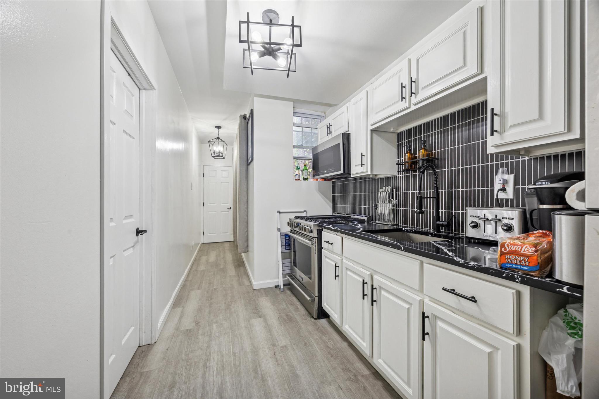 6153 Locust Street, Unit 1 Philadelphia, PA 19139 - Photo 5 of 14 a kitchen with stainless steel appliances granite countertop a sink and cabinets