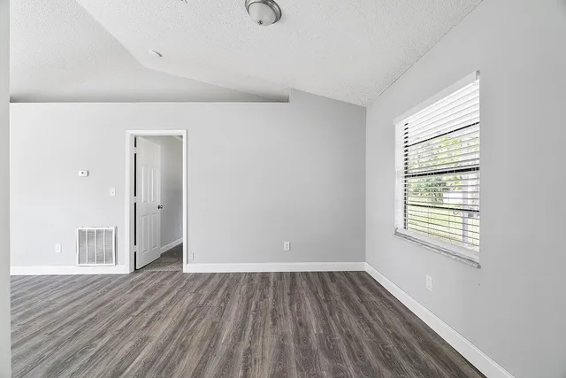 an empty room with wooden floor and windows