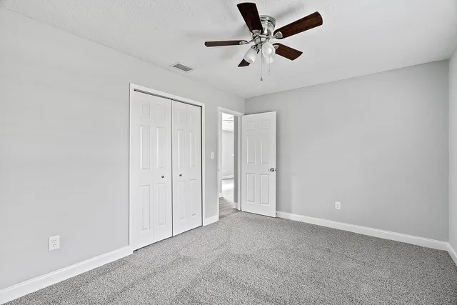 an empty room with a ceiling fan and carpet