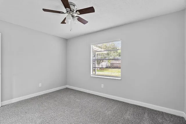 an empty room with windows and fan