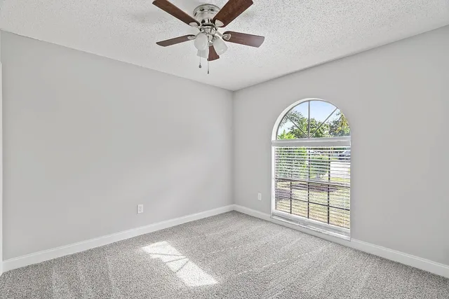 an empty room with windows and ceiling fan