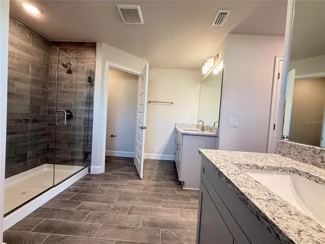 a bathroom with a granite countertop sink a mirror and shower