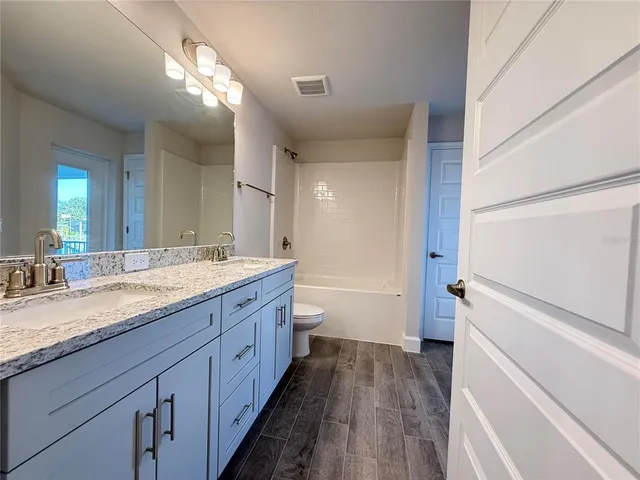 a spacious bathroom with a granite countertop sink mirror and a toilet
