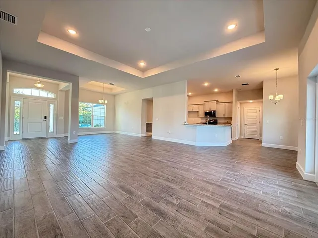 a view of a big room with wooden floor and a kitchen
