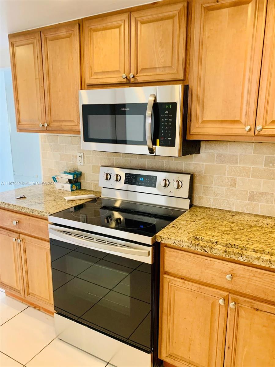 8001 Crespi Boulevard, Unit 2D Miami Beach, FL 33141 - Photo 5 of 12 a kitchen with stainless steel appliances granite countertop white cabinets and a stove
