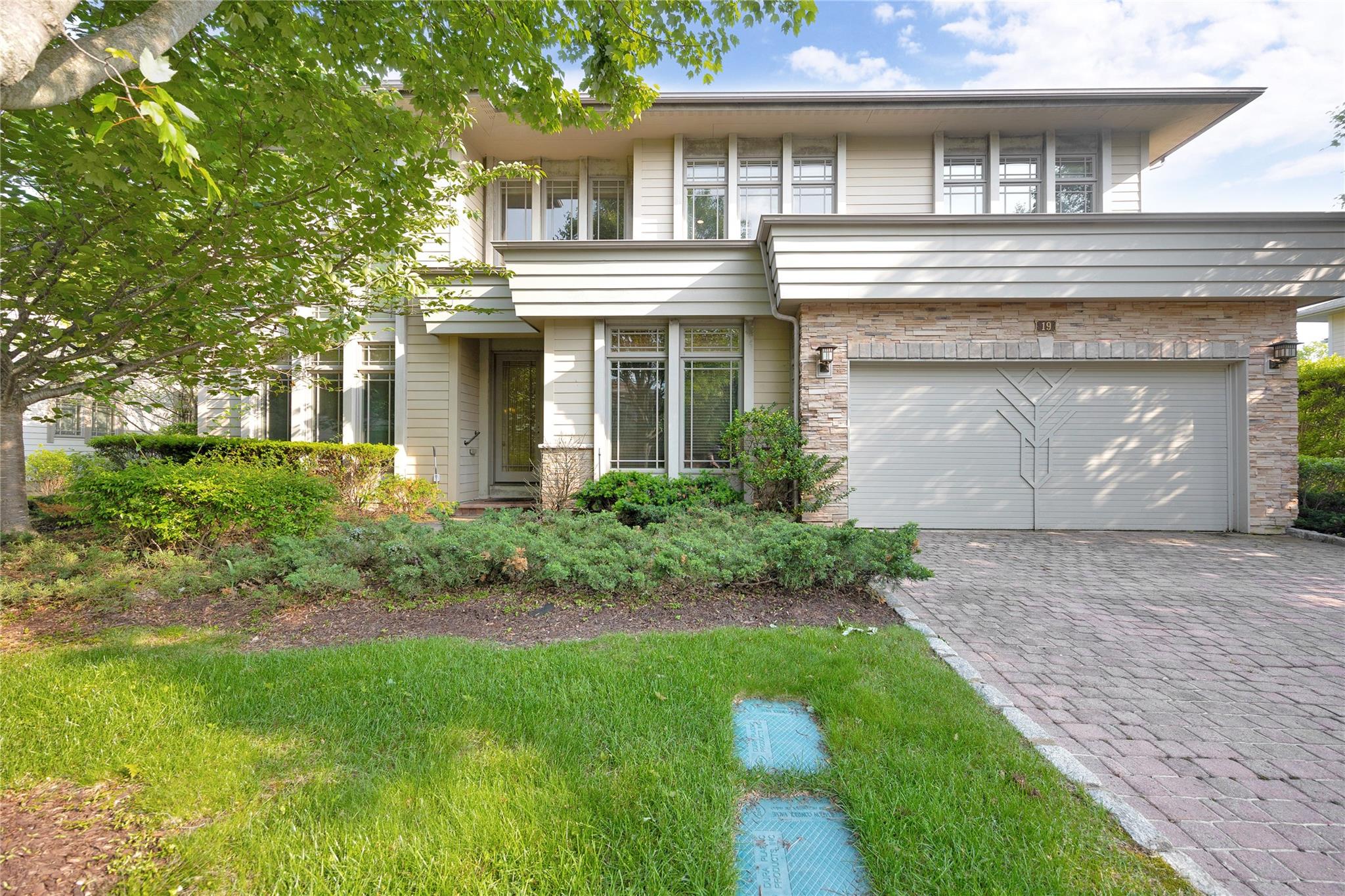 View of front of home with driveway and stone siding