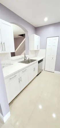 a large white kitchen with a sink a stove and a refrigerator