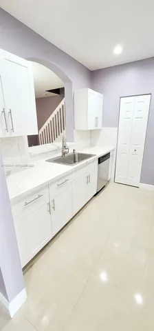 a large white kitchen with a sink a stove and a refrigerator