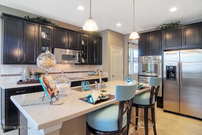 906 East Red House Branch Road St. Augustine, FL 32084 - Photo 6 of 13 a kitchen with stainless steel appliances kitchen island granite countertop a table chairs and a refrigerator