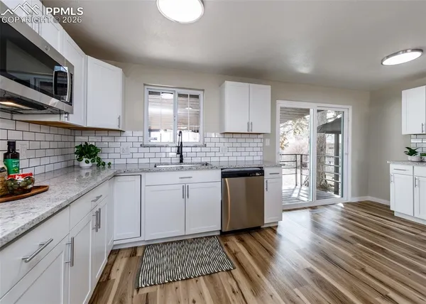 a kitchen with granite countertop a sink a counter space cabinets and stainless steel appliances