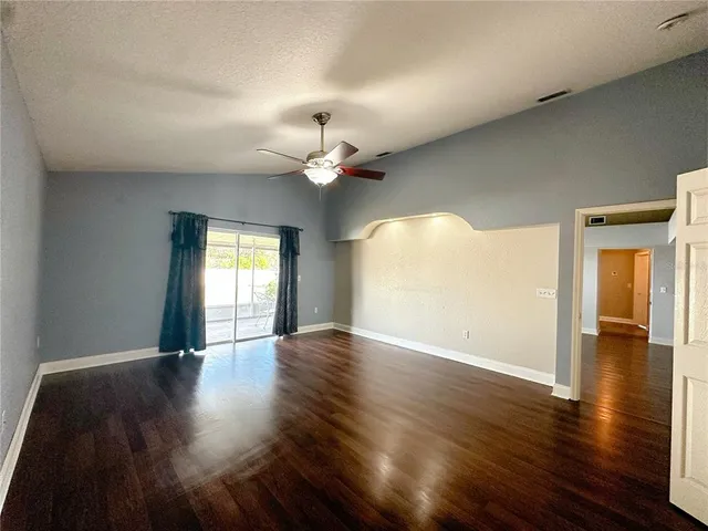 an empty room with wooden floor chandelier and windows