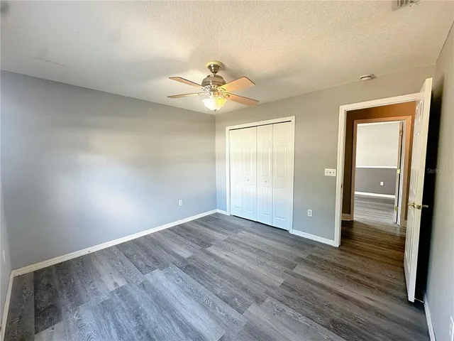 an empty room with wooden floor fan and windows