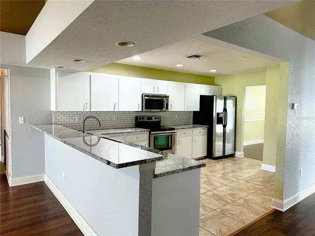 a kitchen with stainless steel appliances granite countertop a sink refrigerator and microwave