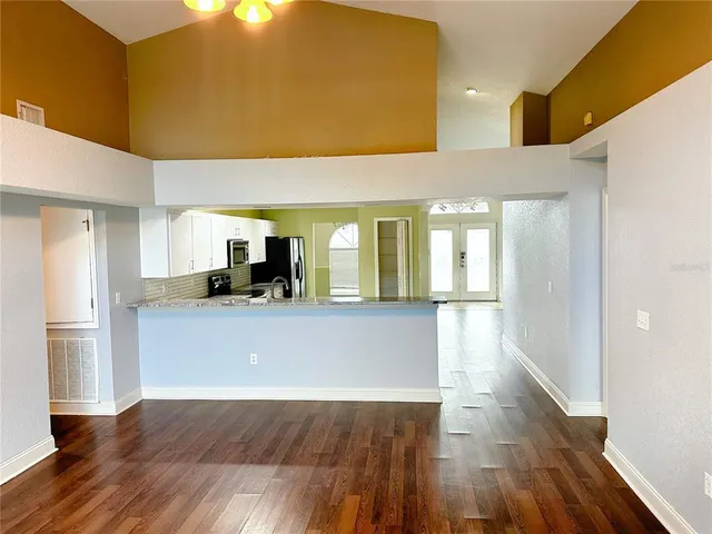 a living room with stainless steel appliances kitchen island wooden floors and view kitchen
