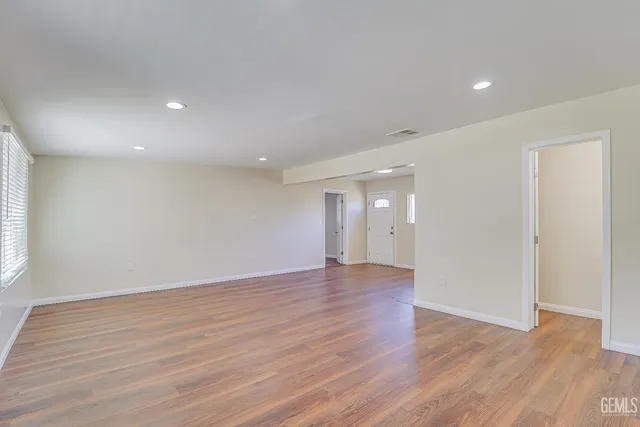 a view of an empty room with wooden floor and window