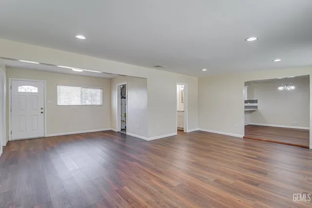 a view of an empty room with wooden floor and window