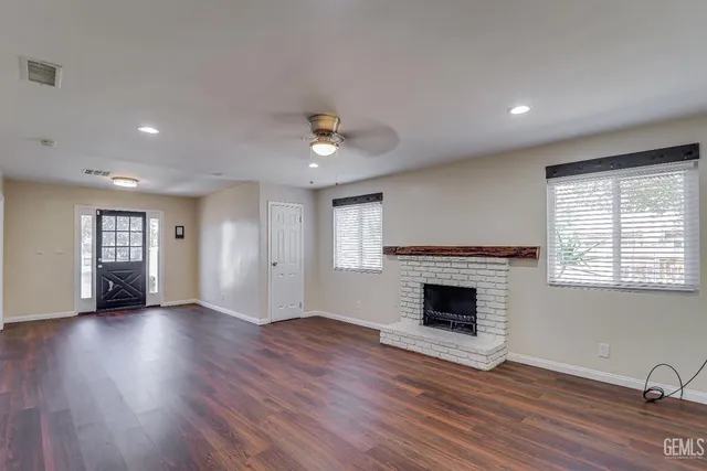 an empty room with windows fireplace and wooden floor