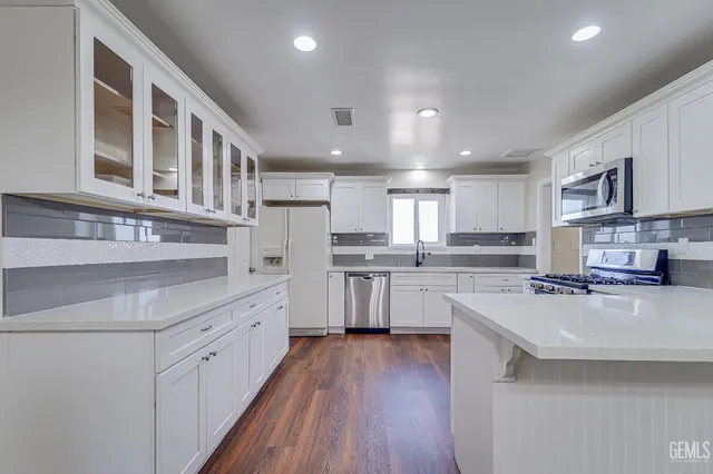 a large kitchen with stainless steel appliances granite countertop a lot of counter space and wooden floors