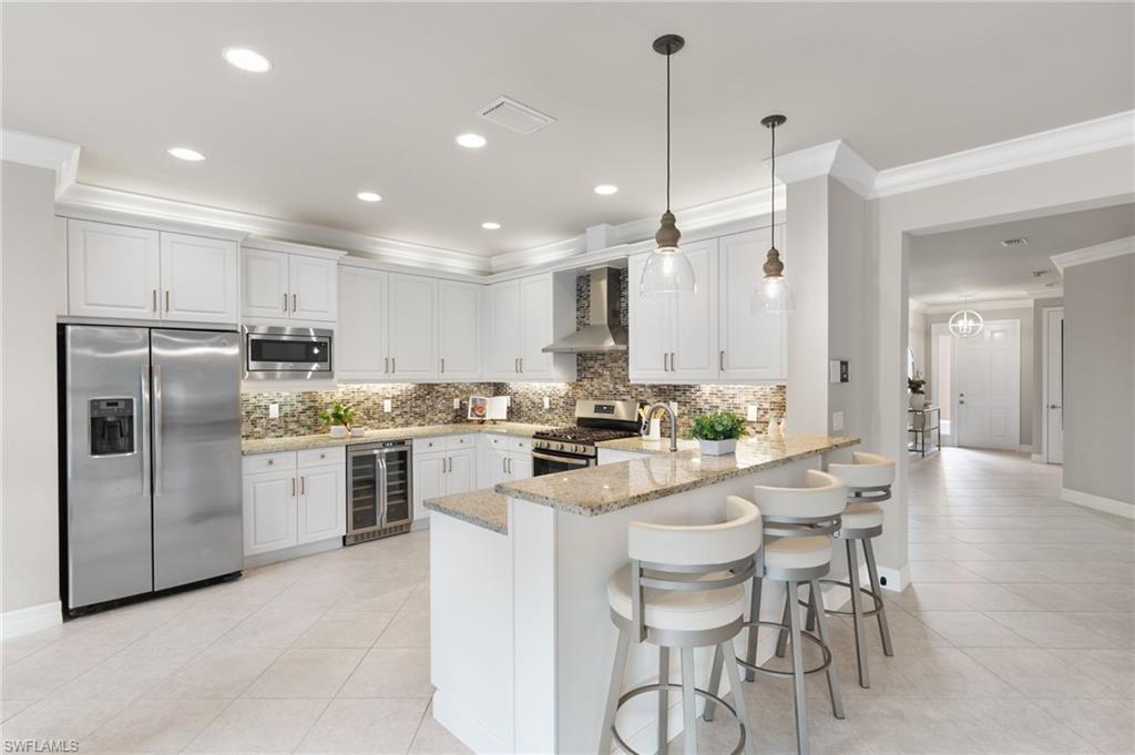 4384 Aurora Street Naples, FL 34119 - Photo 13 of 47 a kitchen with refrigerator a stove and chairs