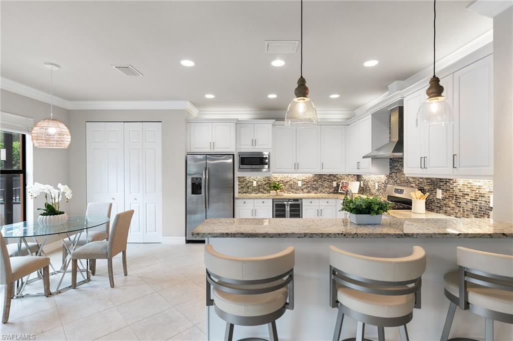 4384 Aurora Street Naples, FL 34119 - Photo 14 of 47 a kitchen with refrigerator and chairs