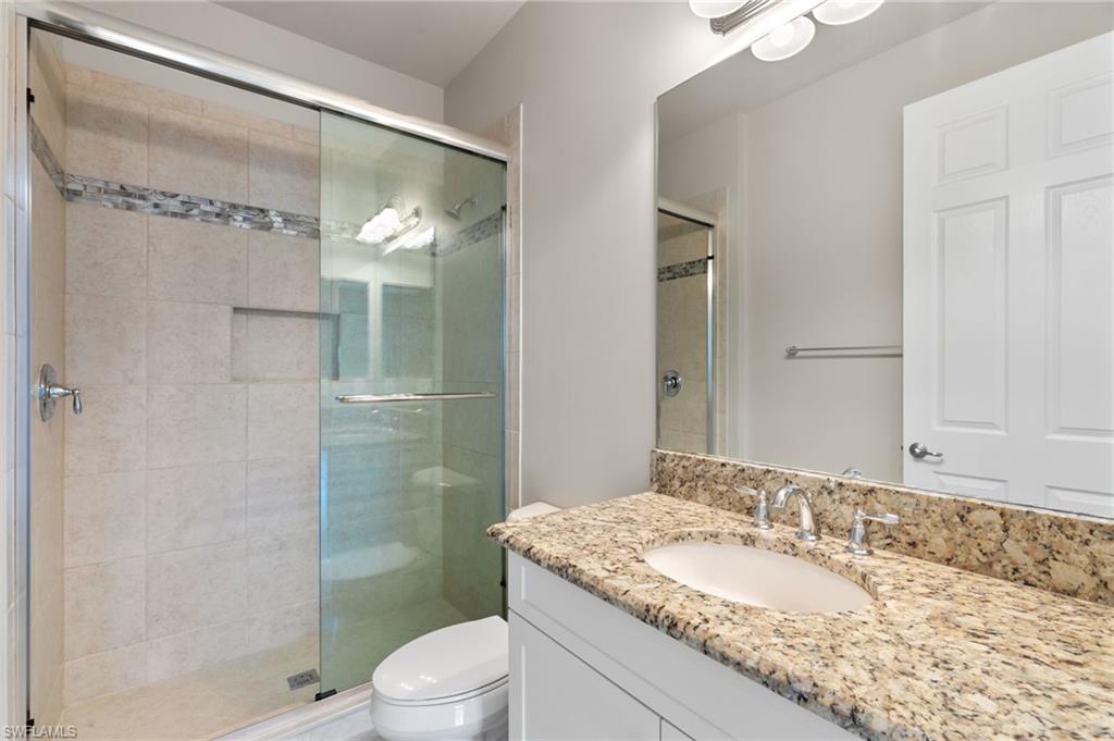 4384 Aurora Street Naples, FL 34119 - Photo 30 of 47 a bathroom with a granite countertop sink toilet and shower