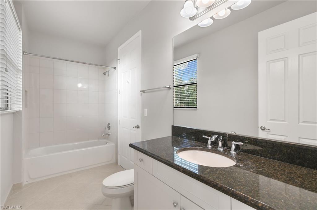 4384 Aurora Street Naples, FL 34119 - Photo 33 of 47 a bathroom with a granite countertop sink a toilet a mirror and shower