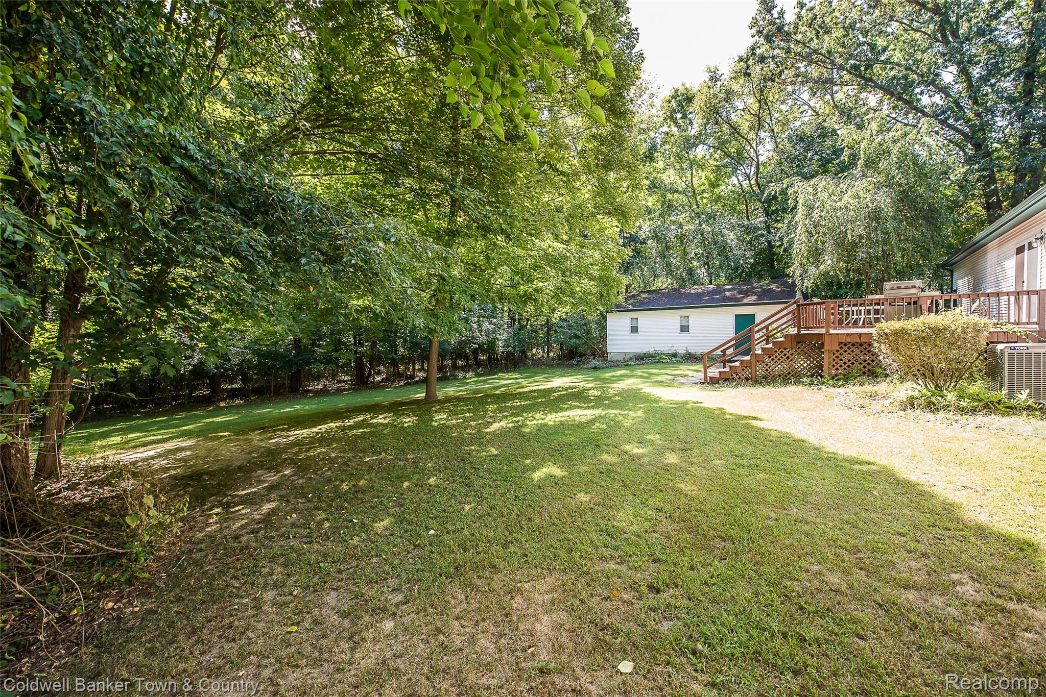 11527 Mcgregor Road Pinckney, MI 48169 - Photo 23 of 26 View of green lawn featuring a wooden deck, stairway, and view of wooded area