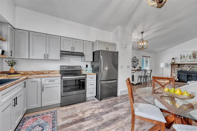 a kitchen with stainless steel appliances a stove a sink dishwasher a refrigerator cabinets and a dining table