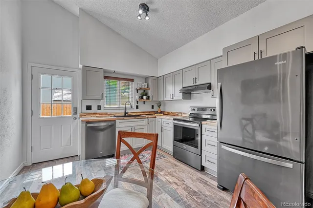 a kitchen with stainless steel appliances granite countertop a refrigerator sink and stove