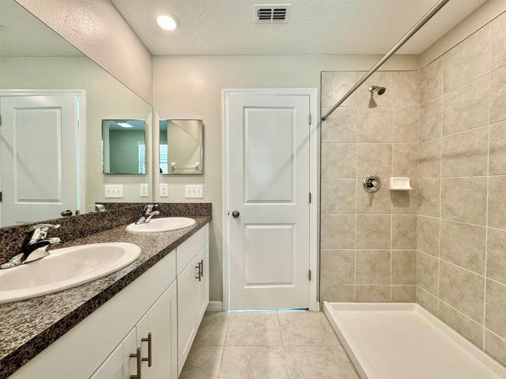 7020 Samuel Ivy Drive Tampa, FL 33619 - Photo 15 of 41 a bathroom with a granite countertop sink mirror and shower