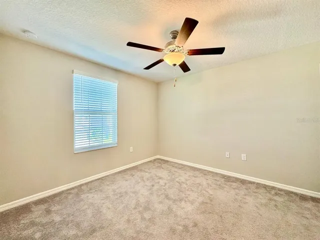 an empty room with a window and a ceiling fan