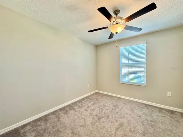 an empty room with a ceiling fan and window