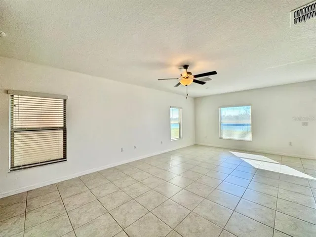 an empty room with windows and ceiling fan
