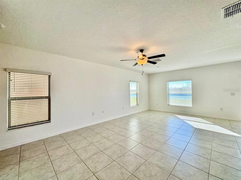 7020 Samuel Ivy Drive Tampa, FL 33619 - Photo 3 of 41 an empty room with windows and ceiling fan