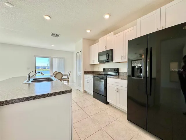 a kitchen with stainless steel appliances granite countertop a refrigerator a sink a stove a microwave and a refrigerator