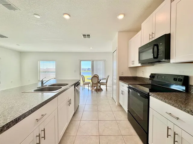 a large kitchen with stainless steel appliances granite countertop a sink and cabinets