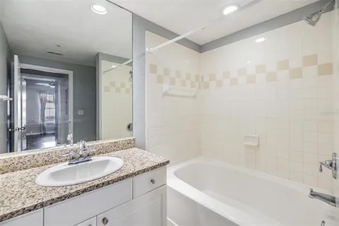 a bathroom with a granite countertop sink a mirror a bathtub and shower