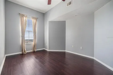 an empty room with wooden floor and windows