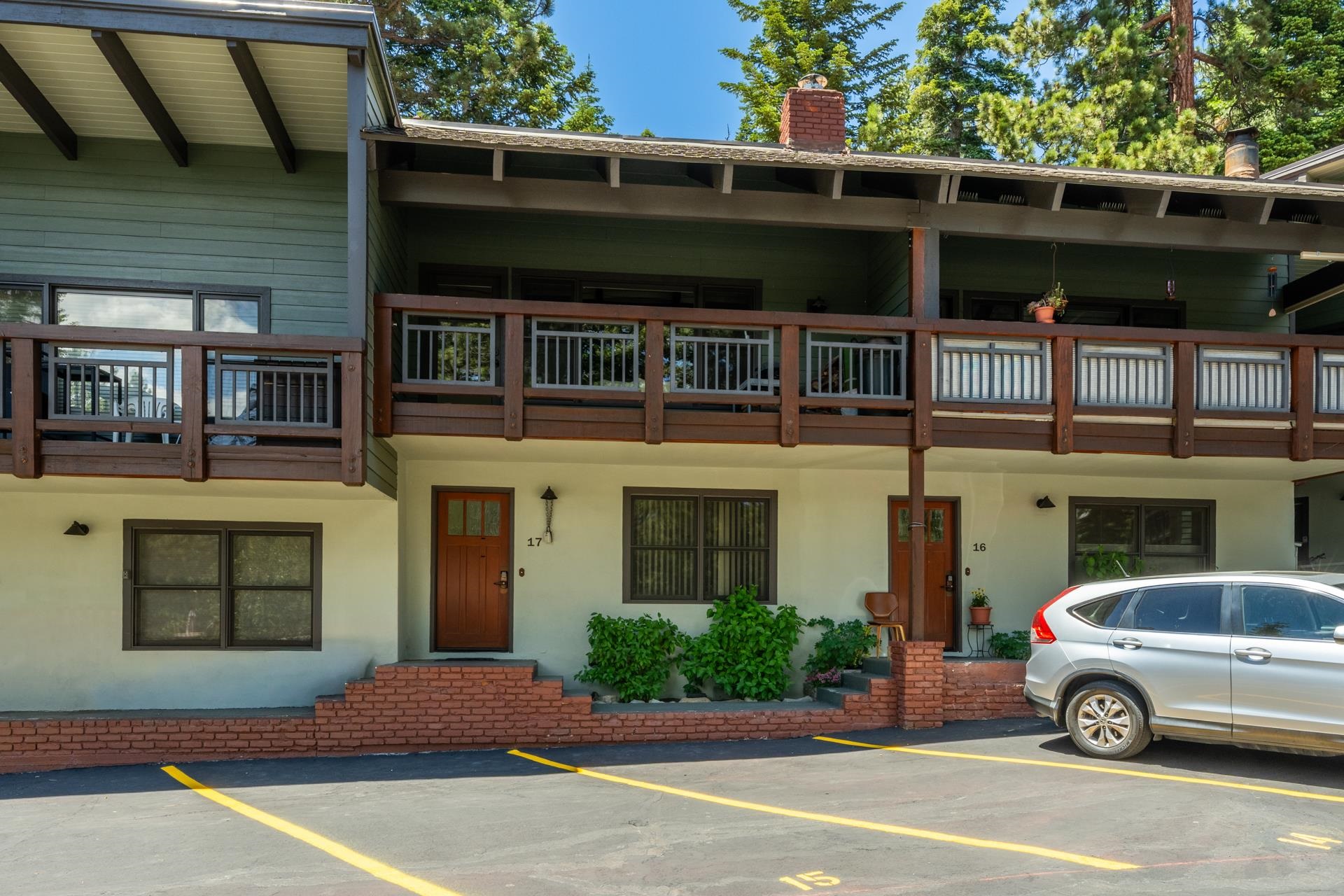 50 Hidden Valley Road, Unit 17 Mammoth Lakes, CA 93546 - Photo 37 of 40 Exterior facade featuring a wood-paneled balcony, light-toned siding, and a brick-accented entryway with a wood door
