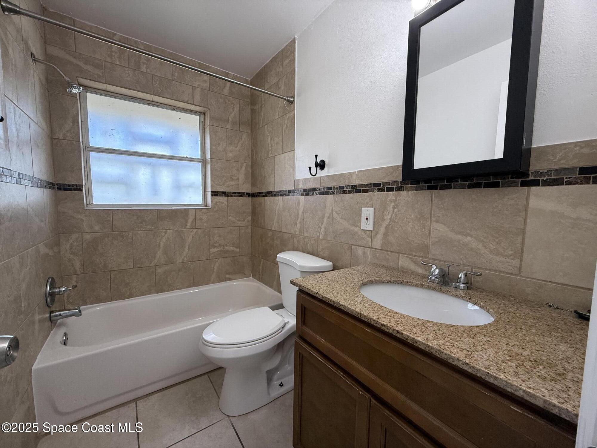 1440 Parkway Drive, Unit 7A Melbourne, FL 32935 - Photo 13 of 27 a bathroom with a granite countertop sink a toilet and a bathtub