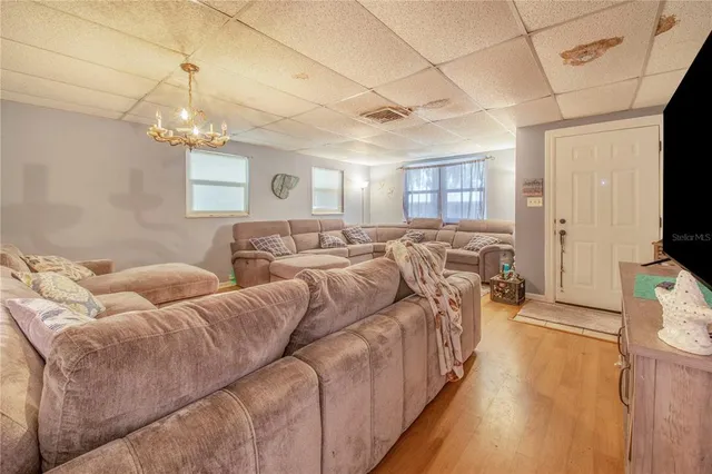 a living room with furniture a flat screen tv and a chandelier