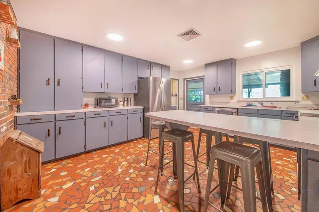 a kitchen with stainless steel appliances granite countertop a stove a sink dishwasher and a refrigerator with wooden cabinets