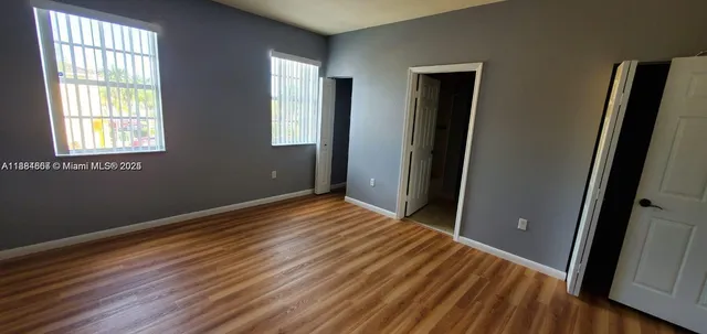 a view of empty room with window and wooden floor