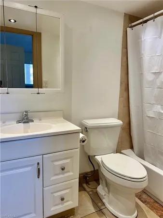 a bathroom with a granite countertop toilet sink and mirror
