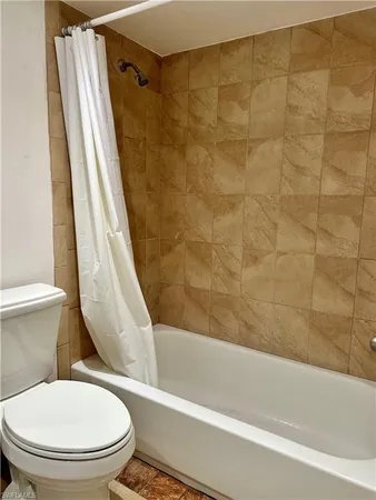 a white toilet sitting next to a bath tub and a shower