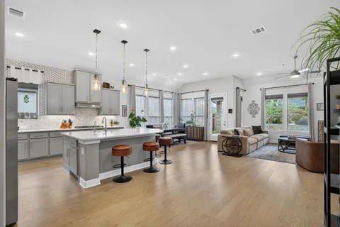 a large living room with stainless steel appliances kitchen island granite countertop a large kitchen island a stove a sink a dining table and chairs with wooden floor