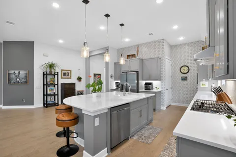 a large kitchen with kitchen island a stove a sink a refrigerator and chairs