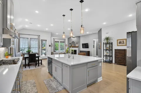 a large kitchen with kitchen island a sink a center island a stove a dining table and chairs
