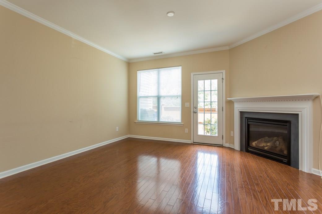 2946 Casona Way Raleigh, NC 27616 - Photo 9 of 25 an empty room with wooden floor fireplace and windows